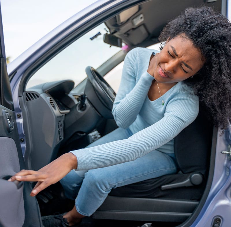 A woman sitting in a car holding her neck in pain, possibly experiencing discomfort from an injury - Chiropractor Kennesaw GA A woman sitting in a car holding her neck in pain, possibly experiencing discomfort from an injury - Chiropractor Kennesaw GA