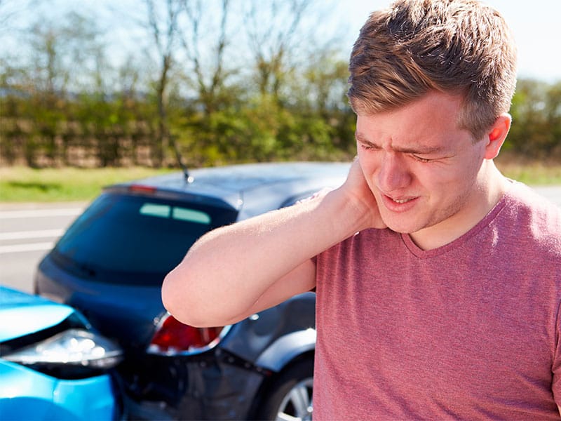 A man holds his neck in pain after a car accident, indicating possible whiplash injury - Auto Accident Chiropractor