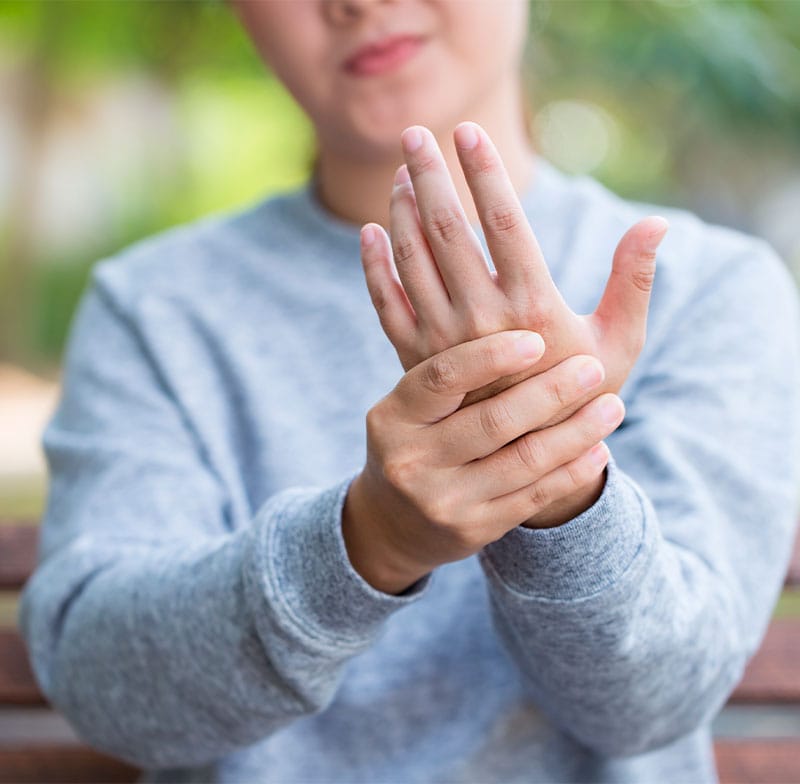A person receiving an injection in the shoulder area from a medical professional wearing gloves - Trigger Point Injections A person holding their hand, possibly indicating discomfort or pain - Neuropathy Treatment