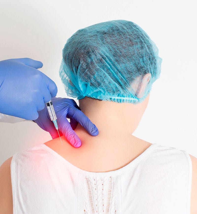A person wearing a hair cap receives an injection in the upper back area from a professional in gloves - Trigger Point Injections