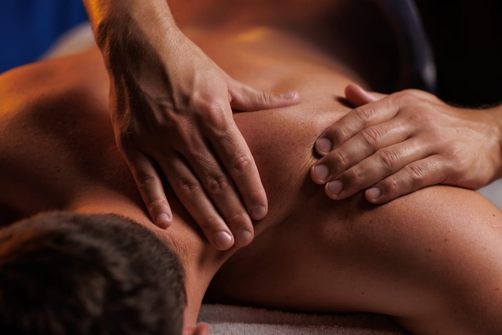 A person receiving a deep tissue massage, with the therapist applying firm pressure to the upper back and shoulder area - Chiropractor Kennesaw GA A person receiving a deep tissue massage, with the therapist applying firm pressure to the upper back and shoulder area - Chiropractor Kennesaw GA